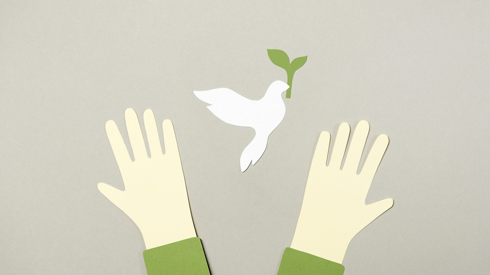 Conceptual image showing cutout hands reaching for a peace dove, symbolizing hope.
